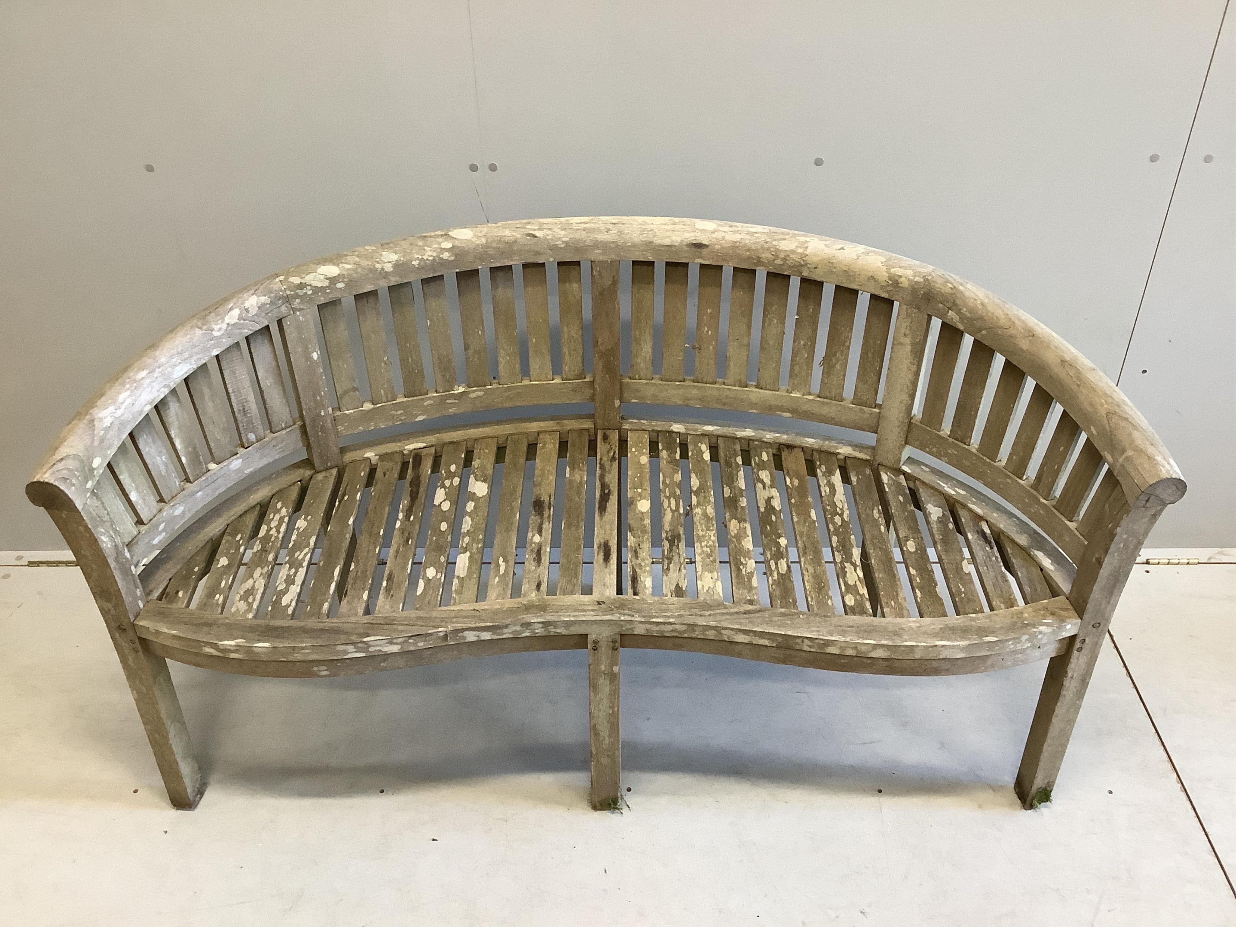 A weathered teak garden banana bench, width 150cm, depth 58cm, height 84cm. Condition -fair